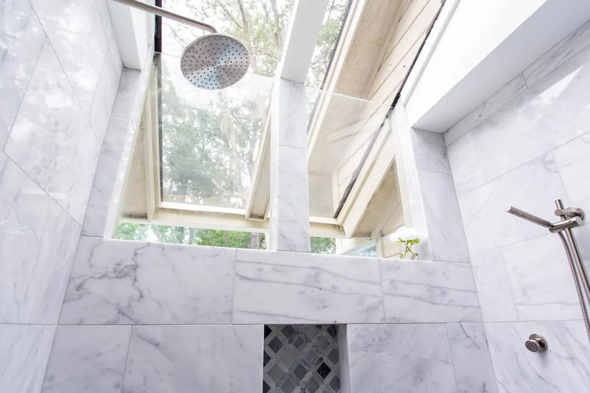 A luxurious bathroom with marble tiles, a rain shower head, and a skylight that fills the space with natural light. The spa-like design evokes relaxation and rejuvenation, ideal for unwinding.