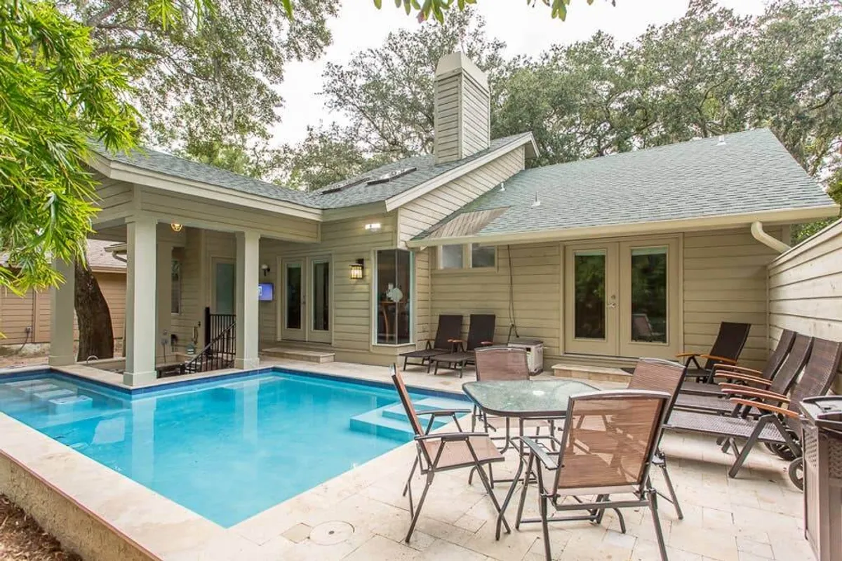 This exterior image centers on a sparkling swimming pool surrounded by an outdoor seating area, modern architecture, and lush landscaped greenery. The clear water and stylish environment set the scene for a resort-like retreat with ample space for relaxing, sunbathing, or social gatherings.