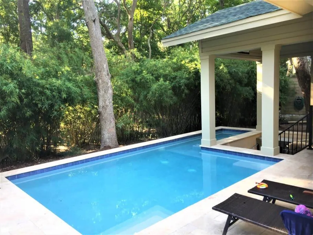 This exterior image showcases a sparkling swimming pool surrounded by lush greenery and an inviting outdoor seating area. The pool is ideal for family swims, poolside games, and relaxing after a day of adventure. The setting feels serene and spacious, suggesting a perfect environment for both active play and peaceful downtime.